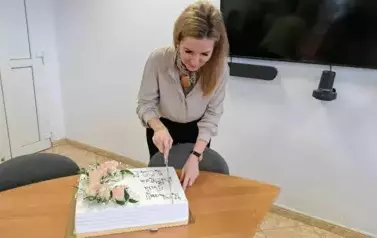 Pani sekretarz gminy rozpoczyna krojenie tortu dla sołtys&oacute;w z okazji ich święta