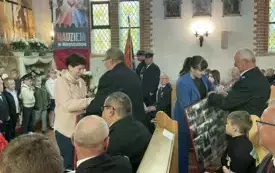 Obchody Dnia Strażaka jednostki KSRG OSP Sośno. Występujące dzieci, strażacy OSP, w&oacute;jt i ksiądz w kościele ustawieni do zbiorowego zdjęcia.