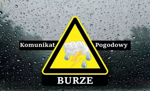 Znak ostrzegawczy z napisem „komunikat pogodowy – burze” na czarnym pasku. W tle szyba pokryta kroplami deszczu. 