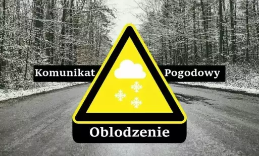 Znak ostrzegawczy z grafiką chmury i płatków śniegu. Napis komunikat pogodowy oblodzenie. W tle oblodzona droga w lesie.