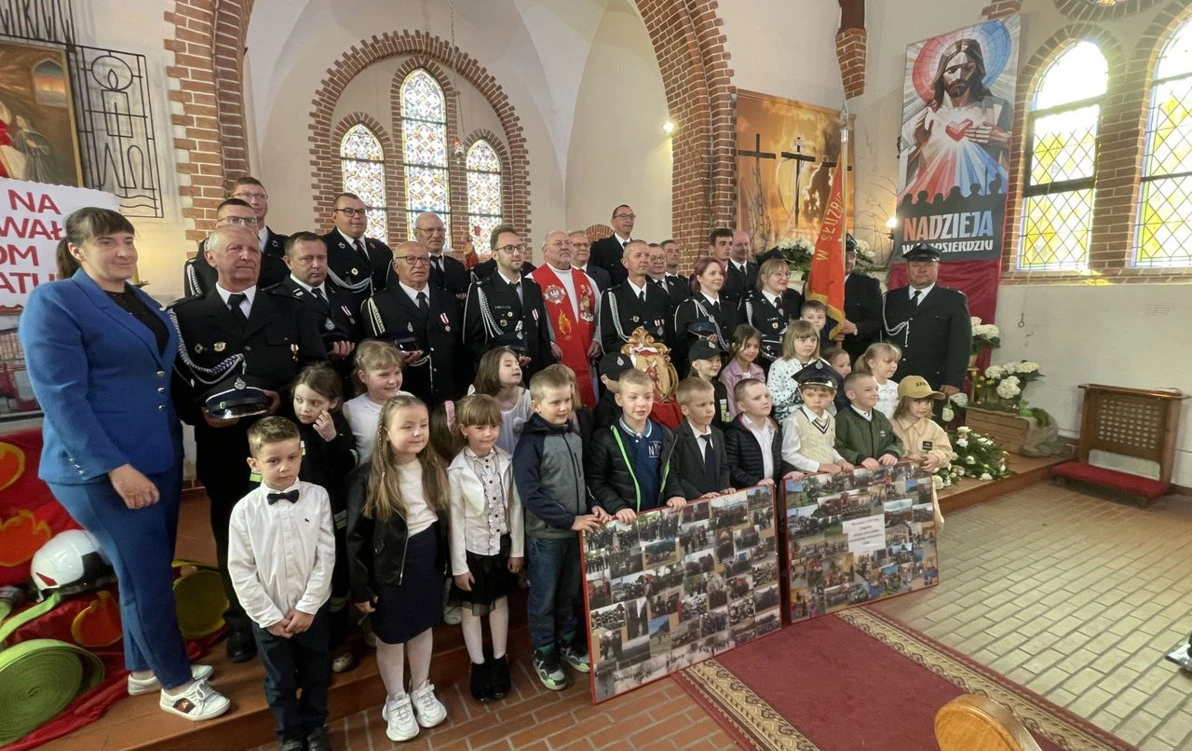 Obchody Dnia Strażaka jednostki KSRG OSP Sośno. Występujące dzieci, strażacy OSP, wójt i ksiądz w kościele ustawieni do zbiorowego zdjęcia.