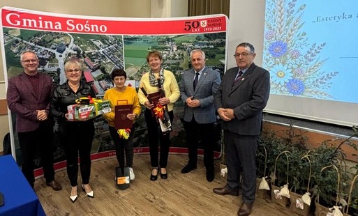 Na zdjęciu widoczni zwycięzcy konkursu " Estetyka Zagrody" wraz z Wójtem Piotrem Dobrzańskim oraz Przewodniczącym Rady Gminy Ryszardem Badzińskim. W tle ścianka ze zdjęciem gminy.